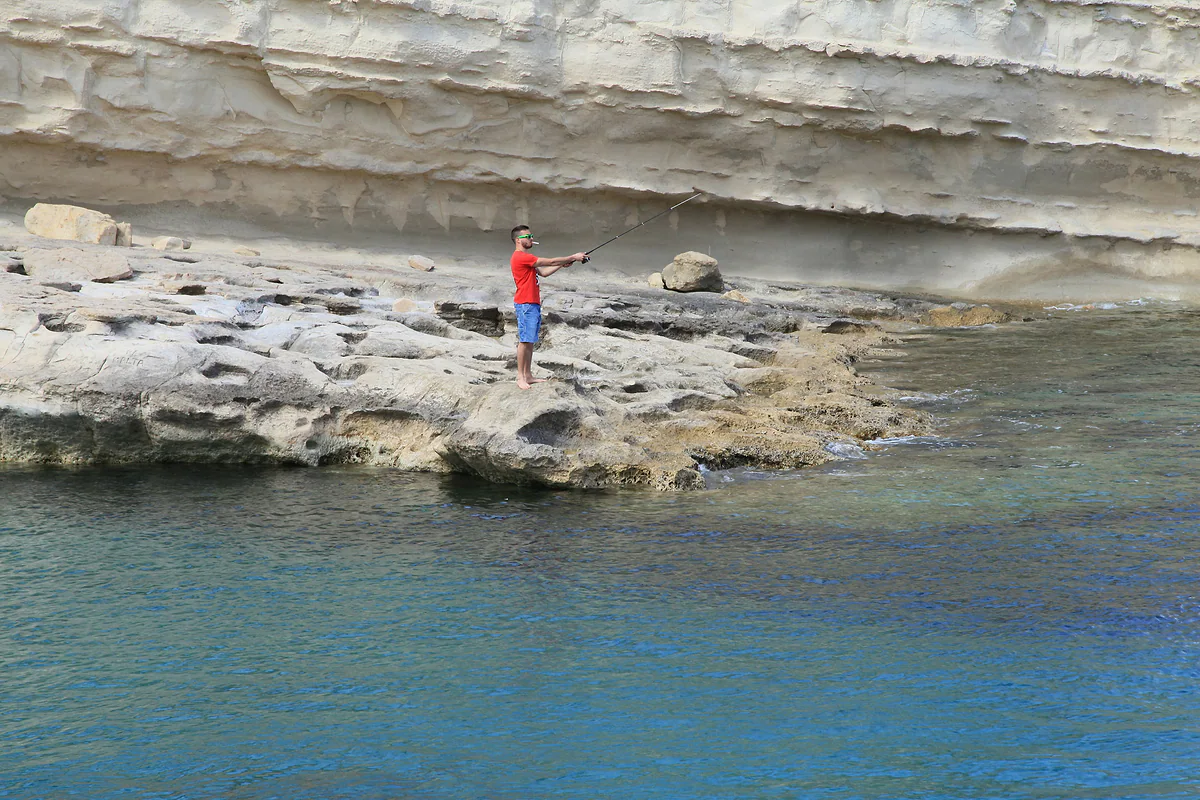 Las rocas blancas de St Peter's Pool, cerca de Marsaxlokk, con un bañista junto a la poza natural de agua turquesa.