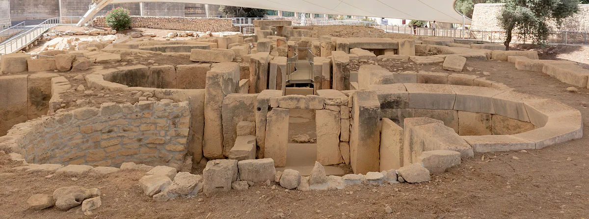 Muros curvos de grandes bloques de piedra de los templos prehistóricos de Tarxien, en Malta, bajo la carpa que los protege.
