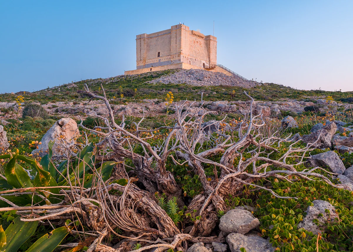 La torre de Santa María de Comino, fortaleza cuadrada de piedra de la Orden de Malta, sobre la meseta de matorral de la isla.
