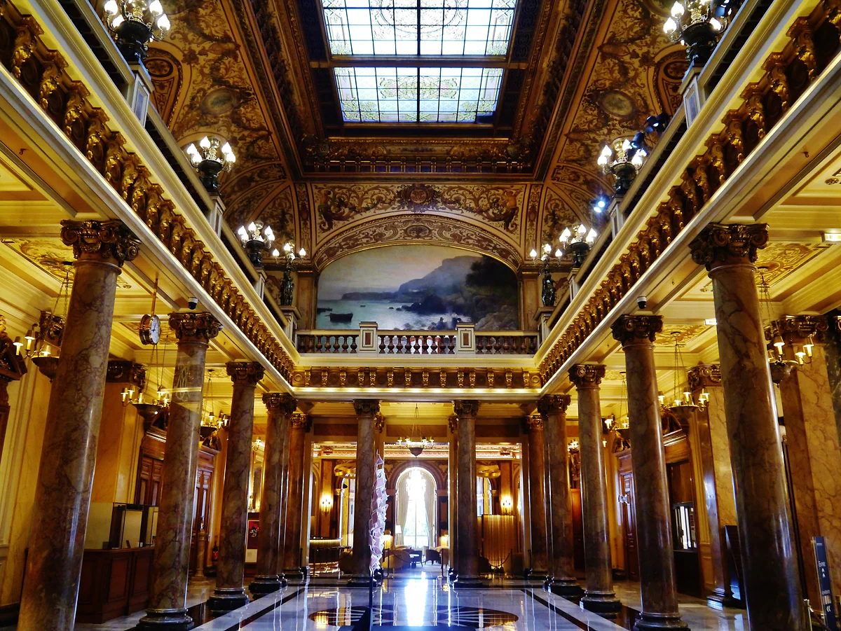El atrio del Casino de Montecarlo, con columnas de mármol, dorados, lámparas y la claraboya del techo.