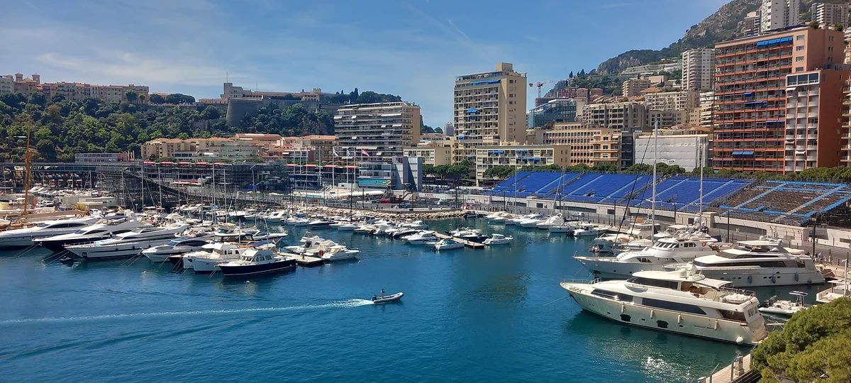 Yates amarrados en el puerto de Hércules, con las tribunas azules del Gran Premio y los edificios de Monte-Carlo detrás.