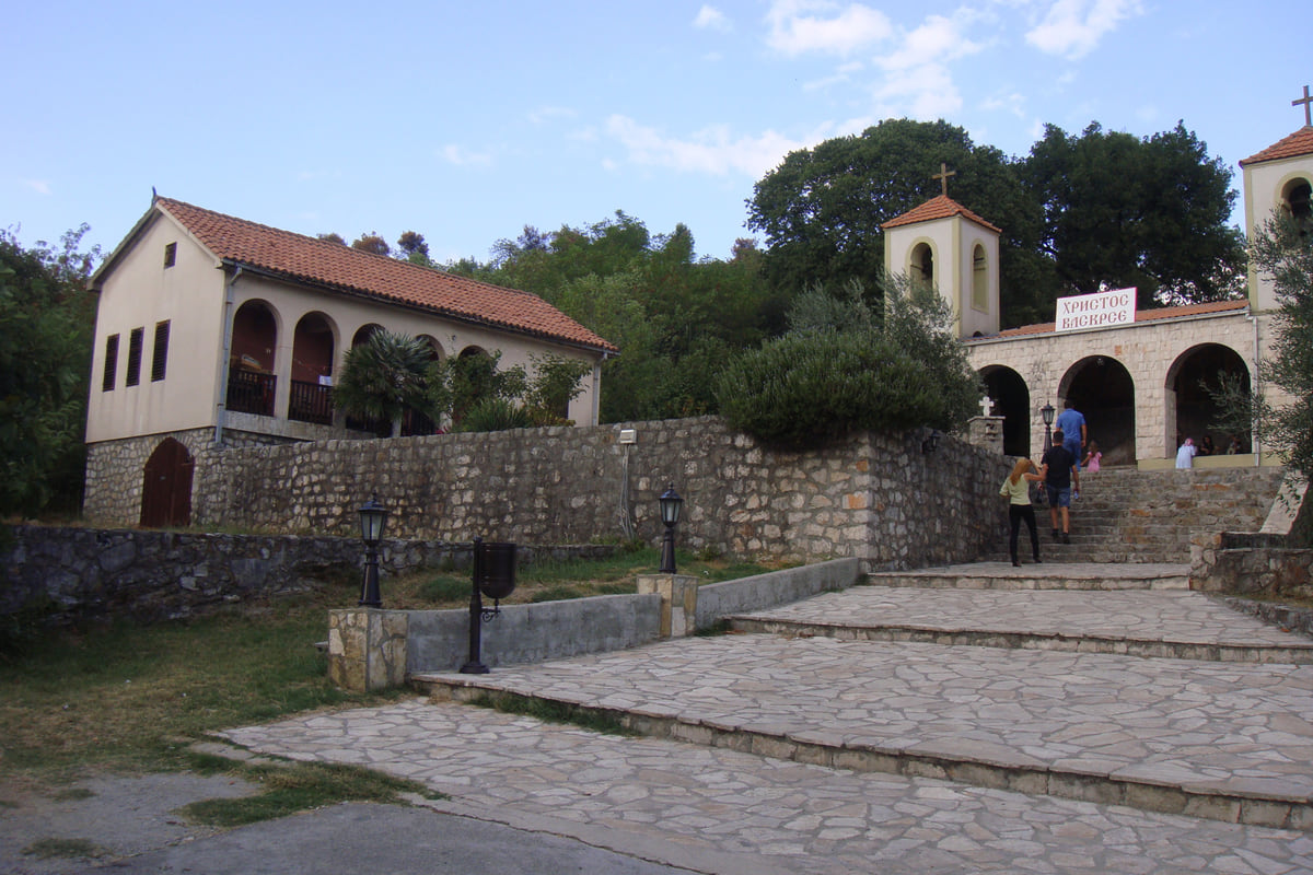 The entrance to Dajbabe Monastery near Podgorica, with stone steps, the arched porch and the bell tower above the cave church