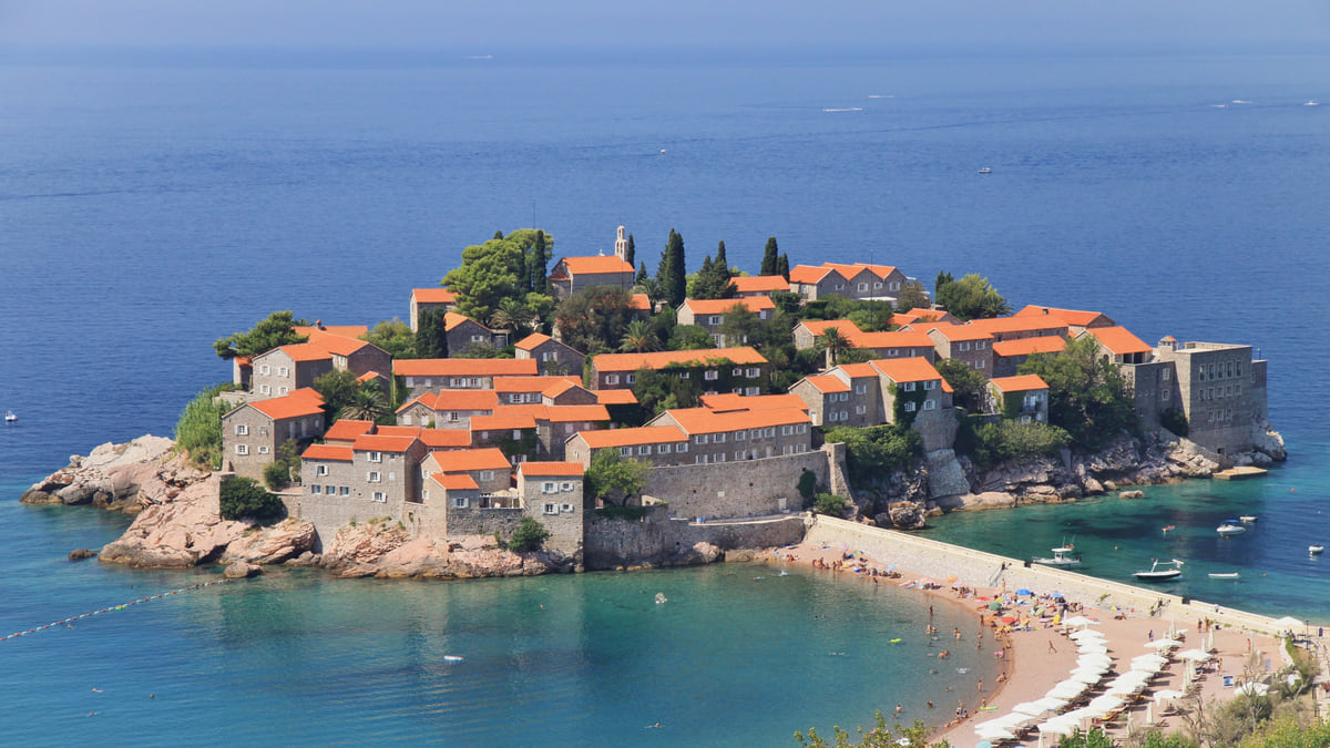 Sveti Stefan joined to the shore by a sandy isthmus, its stone houses and red roofs ringed by turquoise water