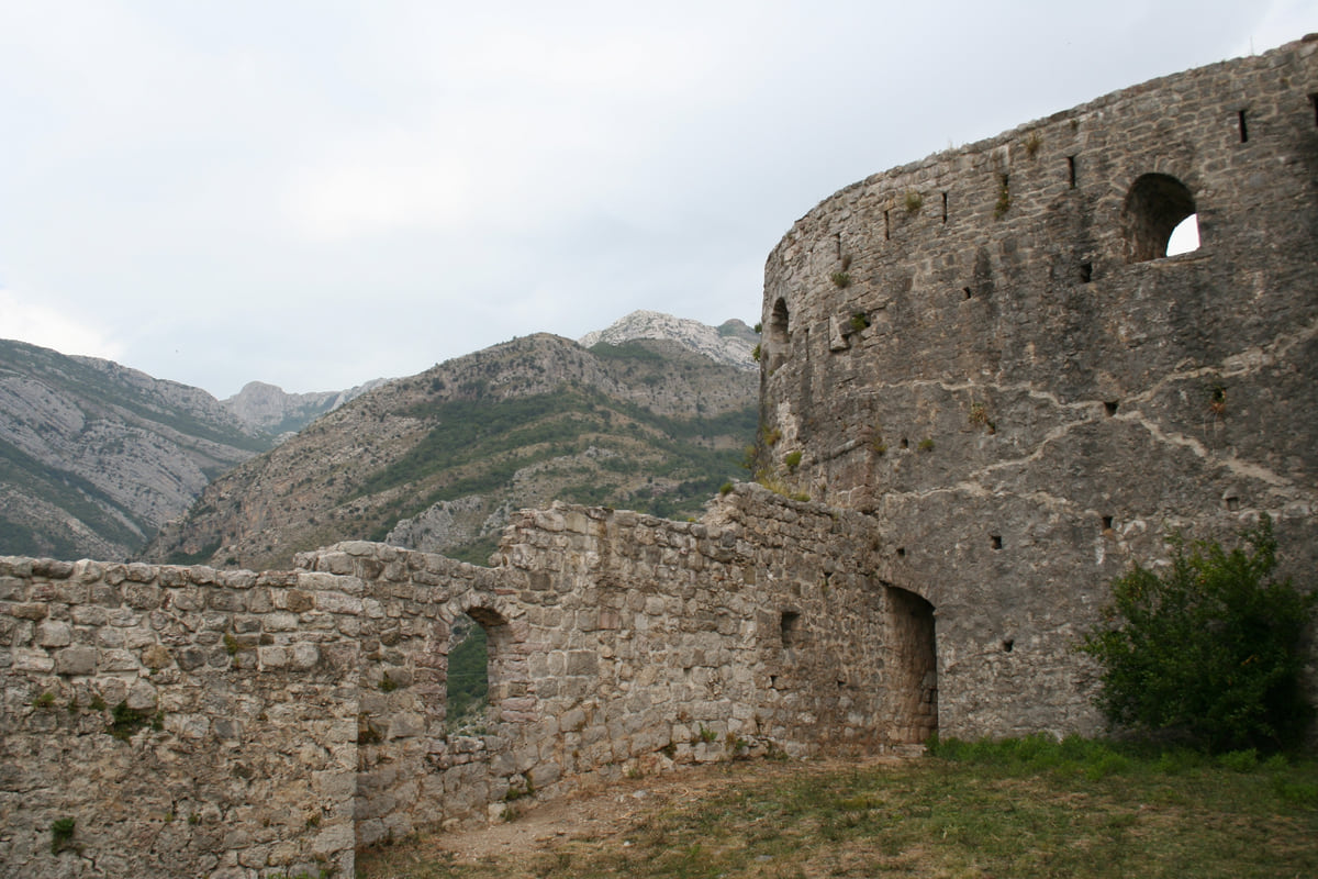 The walls and a round tower of Stari Bar, the ruined old town above Bar, with rocky mountains in the background