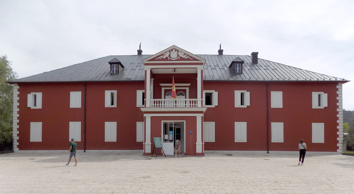 The red front of King Nikola's Palace in Cetinje, with white window frames and a balcony above the main entrance