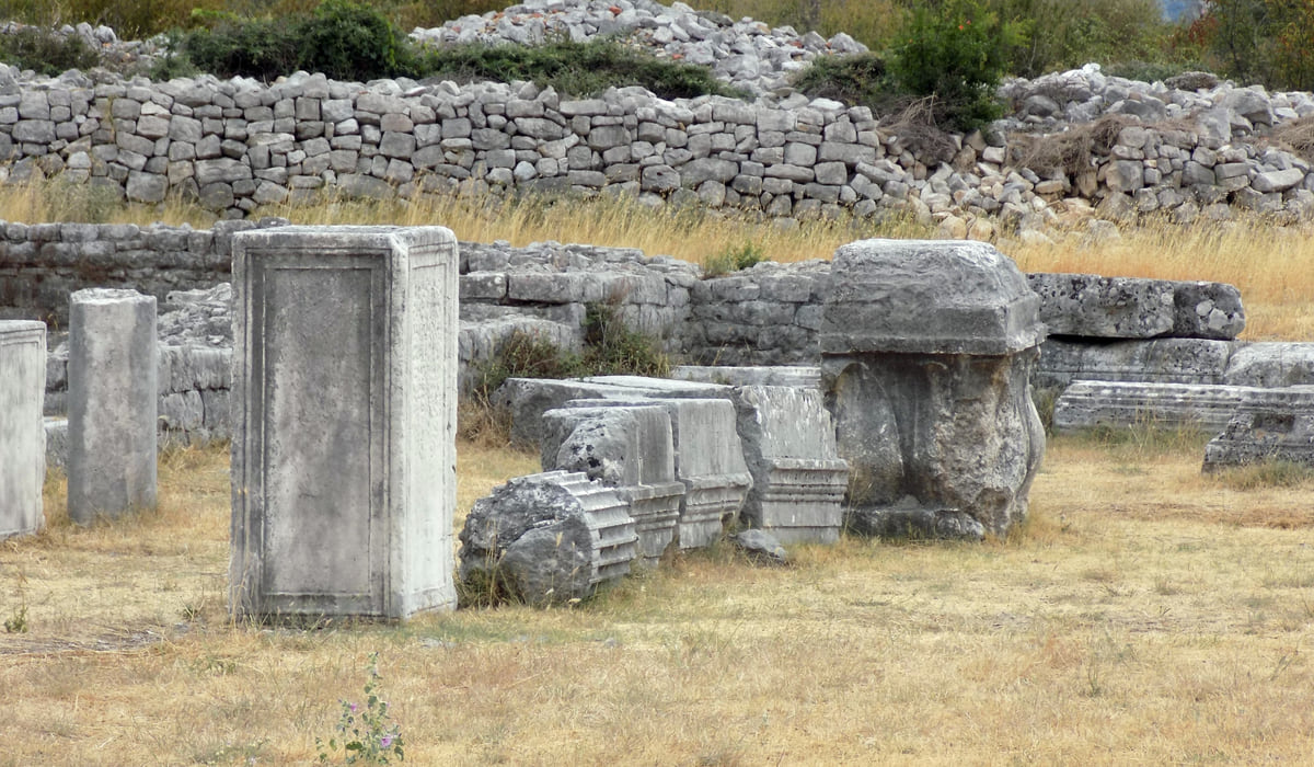 Columns and stone blocks of the Roman town of Doclea near Podgorica, among dry grass and low walls