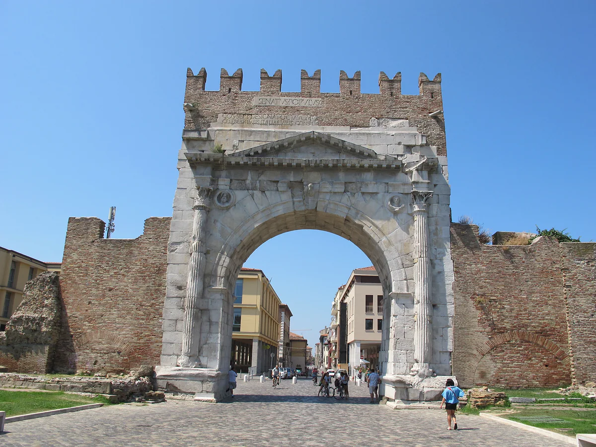 El Arco de Augusto de Rímini, arco romano de piedra con almenas medievales, abierto hacia la calle del centro.