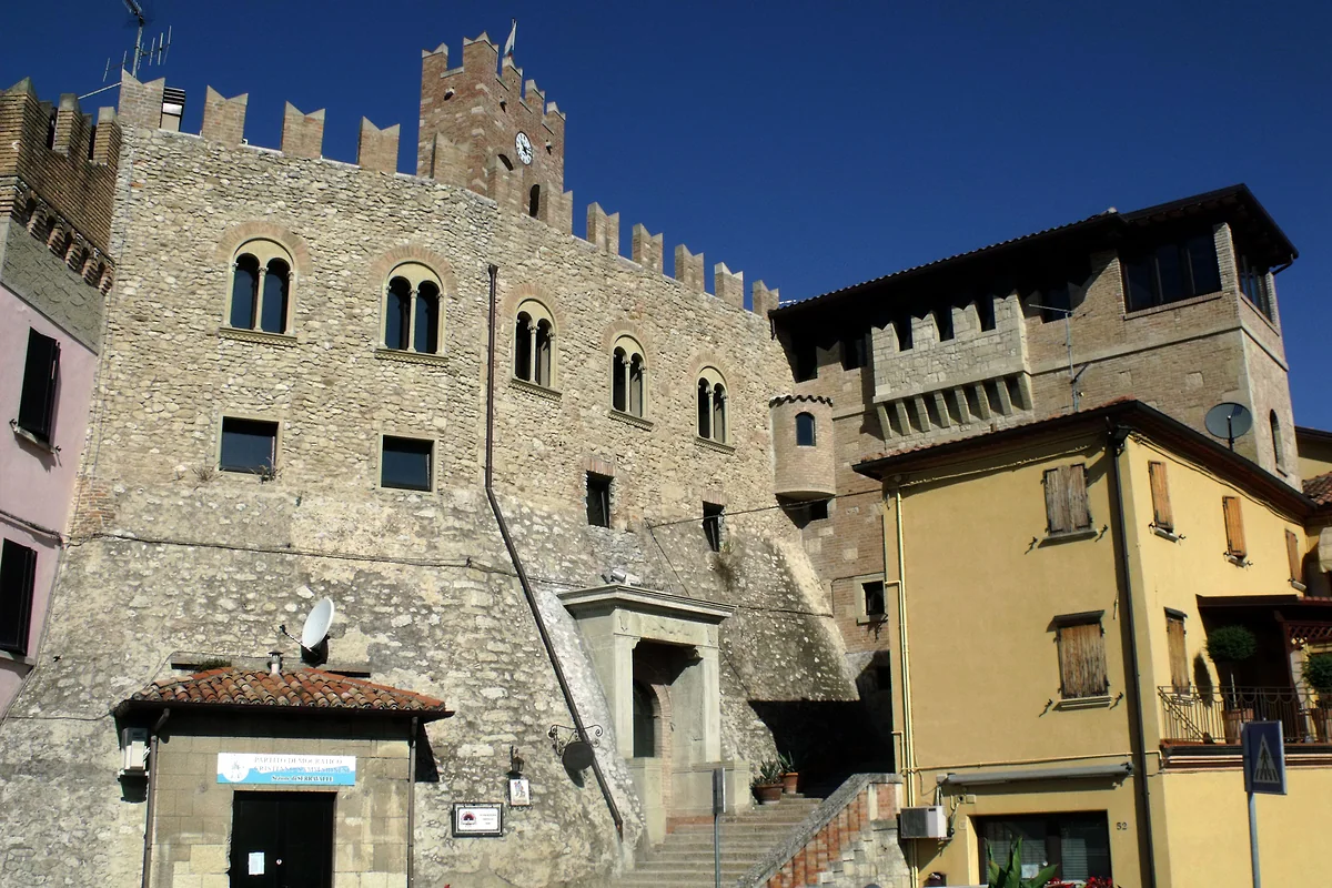 El castillo de Serravalle, con sus muros de piedra, las almenas y la torre, bajo un cielo azul intenso.