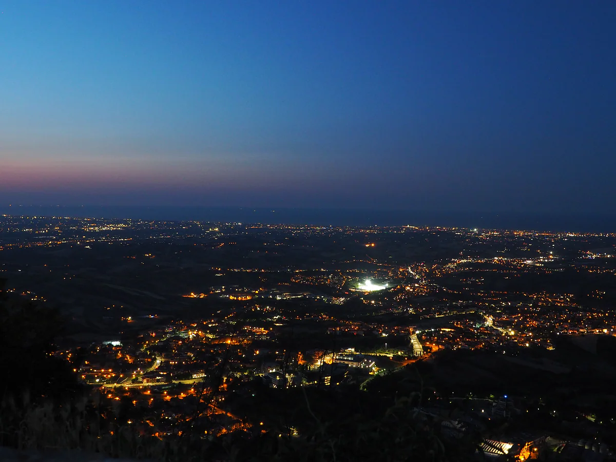 Las luces de la llanura y de la costa de Rímini vistas de noche desde el Titano, con el último resplandor en el horizonte.