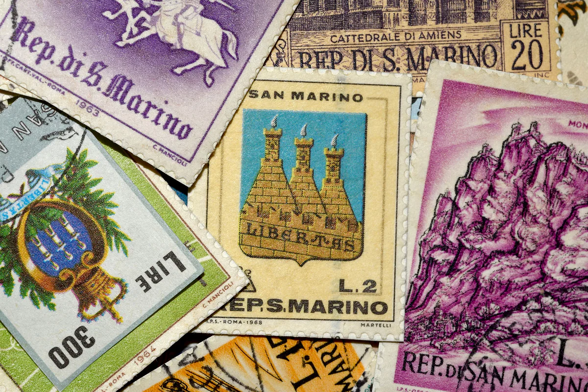 Sellos antiguos de San Marino amontonados, con las tres torres, el escudo y el Monte Titano en sus dibujos.