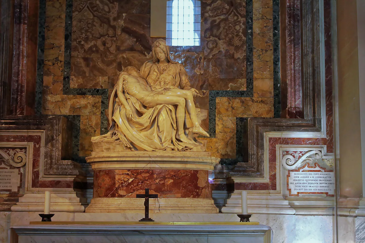La Piedad de Miguel Ángel en su capilla de la Basílica de San Pedro, sobre el altar con un crucifijo y dos candeleros.